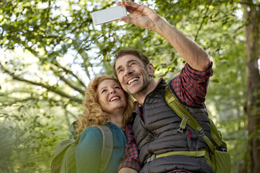 Hiking couple taking selfies with smart phone in forest - FMKF03344