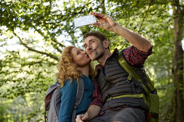 Hiking couple taking selfies with smart phone in forest - FMKF03345