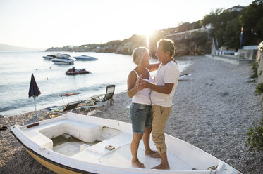 Älteres Paar tanzt zusammen auf einem Boot am Strand in der Abenddämmerung - HAPF01261