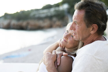 Senior couple relaxing together on the beach at evening twilight - HAPF01264