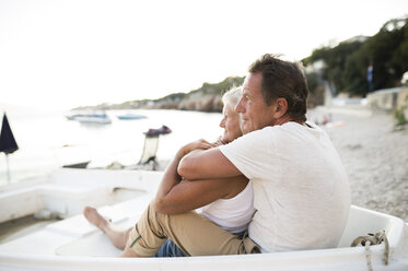 Senior couple relaxing in a boat on the beach in the evening - HAPF01265