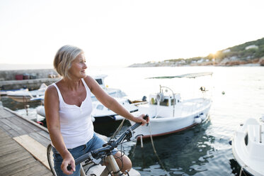 Senior woman with bicycle on a jetty - HAPF01270