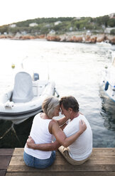 Senior couple sitting head to head on jetty - HAPF01274