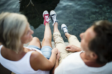 Senior couple sitting on jetty wearing sneakers - HAPF01276