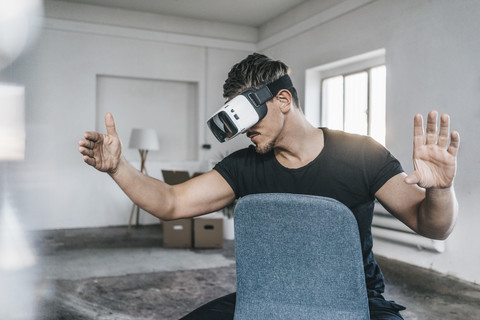 Man sitting on chair in empty loft wearing VR glasses stock photo