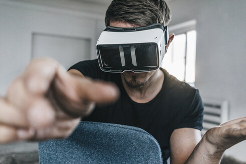 Mann sitzt auf einem Stuhl und trägt eine VR-Brille - KNSF00843