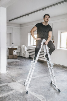Mann sitzt auf Leiter in leerem Dachboden - KNSF00844
