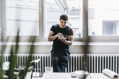 Mann benutzt transparentes mobiles Gerät im Büro - KNSF00858