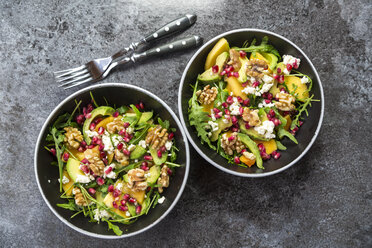 Two bowls of avocado salad with rocket, pomegranate seed, kaki, feta and walnuts - SARF03100