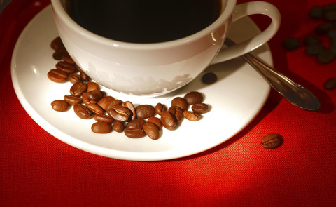 Cup of coffee and roasted coffee beans on red ground stock photo