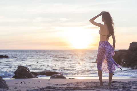 Schöne junge Frau im Bikini am Strand bei Sonnenuntergang, lizenzfreies Stockfoto