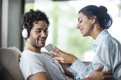 Young couple at home with smartphone and headphones stock photo