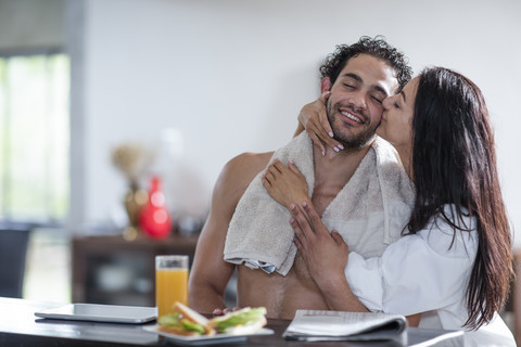 Young woman kissing boyfriend at home during breakfast stock photo