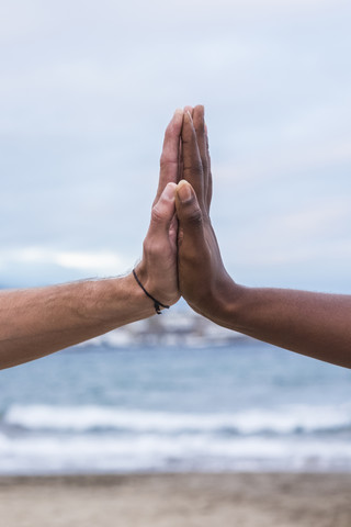 Nahaufnahme von zwei sich berührenden Händen am Strand, lizenzfreies Stockfoto