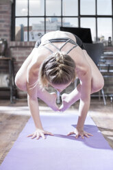 Young woman doing acrobatic yoga exercise in studio - ZEF12053