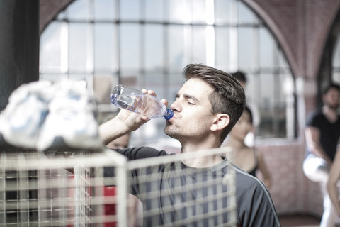 Junger Mann macht eine Erfrischungspause im Fitnessraum, lizenzfreies Stockfoto