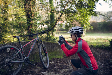 Mountainbiker fotografiert im Wald mit seinem Smartphone - RAEF01605