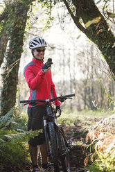 Mountainbiker benutzt Smartphone im Wald - RAEF01614