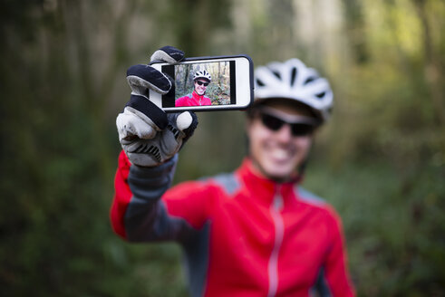 Mountain biker taking selfie with his smart phone - RAEF01617