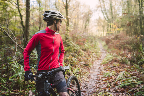 Junger Mann beim Mountainbiken im Wald - RAEF01620