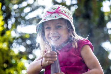 Porträt eines lächelnden kleinen Mädchens, das Wasser versprüht - JFEF00814