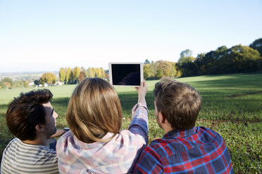 Friends sitting in the countryside taking a selfie with a tablet - FMKF03354