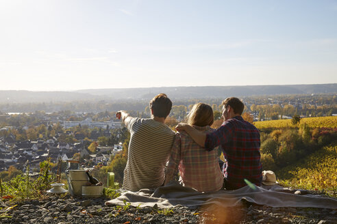 Friends sitting on a hill above a town - FMKF03359