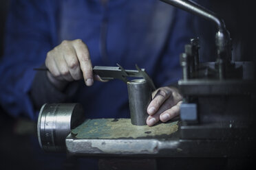 Woman using Vernier caliper in workshop to measure diameter - ZEF12116