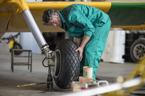 Mechaniker im Hangar, der Leichtflugzeuge repariert, Reifen repariert, lizenzfreies Stockfoto