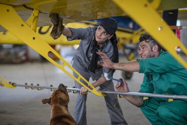 Mechaniker mit Hund im Hangar bei der Reparatur von Leichtflugzeugen - ZEF12149