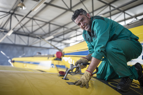 Mechanic in hangar refilling tank of light aircraft stock photo