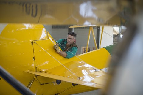 Mechanic in hangar repairing light aircraft stock photo