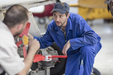 Mechaniker im Hangar bei der Reparatur von Leichtflugzeugen, lizenzfreies Stockfoto