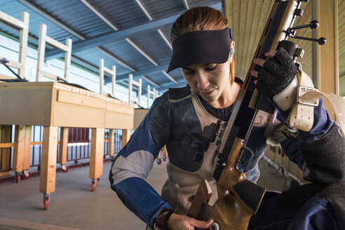 Frau prüft ihr Sportgewehr auf einem Schießstand - ABZF01698
