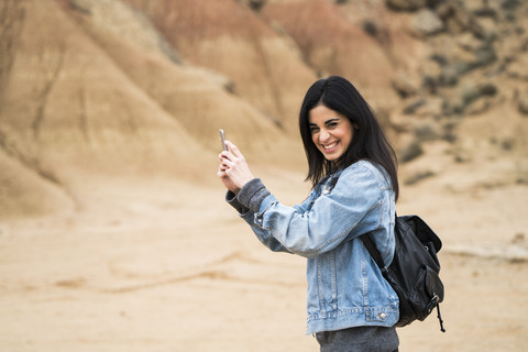 Spain, Navarra, Bardenas Reales, laughing young woman in nature park taking selfie with cell phone stock photo