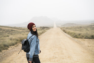 Spain, Navarra, Bardenas Reales, smiling young woman walking in nature park - KKAF00257