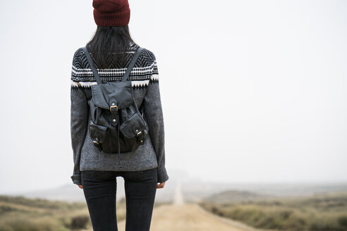 Spain, Navarra, Bardenas Reales, back view of young woman standing in nature park - KKAF00259