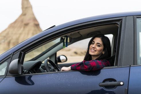 Spanien, Navarra, Bardenas Reales, glückliche junge Frau schaut aus dem Autofenster - KKAF00261