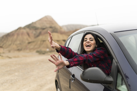 Spain, Navarra, Bardenas Reales, screaming and waving young woman leaning out of car window stock photo