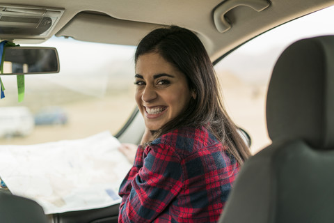 Porträt einer lachenden jungen Frau mit Landkarte in einem Auto, lizenzfreies Stockfoto