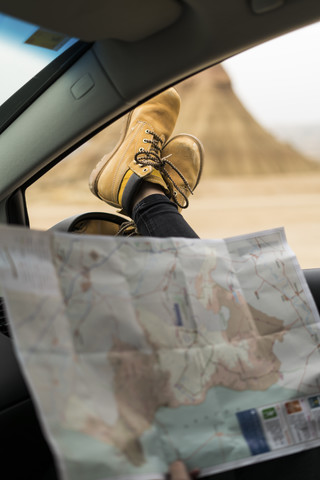 Spanien, Navarra, Bardenas Reales, Beine einer jungen Frau, die sich aus dem Autofenster lehnt, lizenzfreies Stockfoto