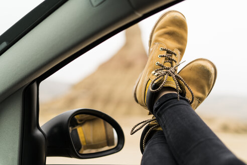 Spanien, Navarra, Bardenas Reales, Beine einer jungen Frau, die sich aus dem Autofenster lehnt - KKAF00268