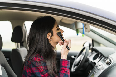 Young woman applying make up on passenger seat of a car - KKAF00269