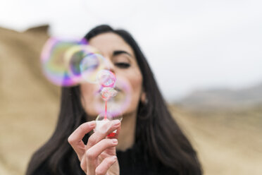Young woman blowing soap bubbles - KKAF00282