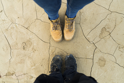 Füße eines Paares, das auf getrocknetem, rissigem Boden steht, lizenzfreies Stockfoto