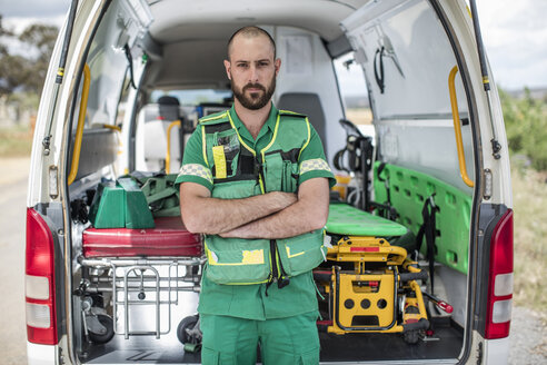 Paramedic standing with arms crossed in front of ambulance - ZEF12172