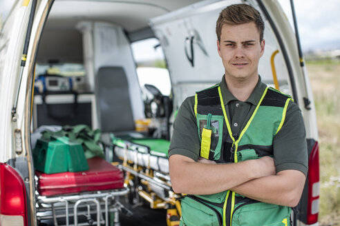 Paramedic standing with arms crossed in front of ambulance - ZEF12174