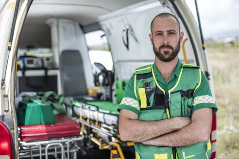 Paramedic standing with arms crossed in front of ambulance - ZEF12175