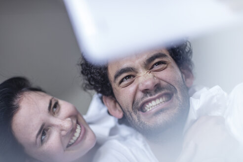 Smiling young couple together in bed with a tablet - ZEF12188