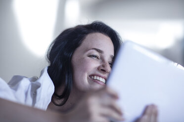Lächelnde junge Frau im Bett mit Tablet - ZEF12193